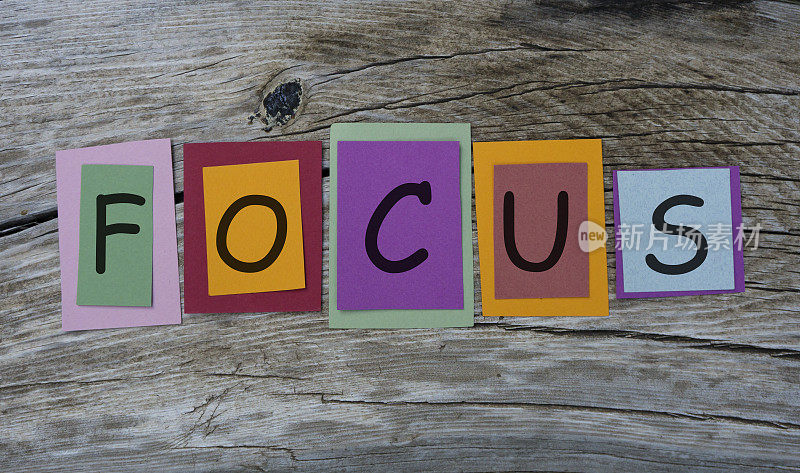 Focus word written on colorful sticky notes on wooden background.